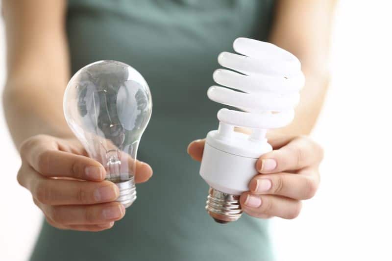 Hands holding traditional and energy efficent lightbulbs